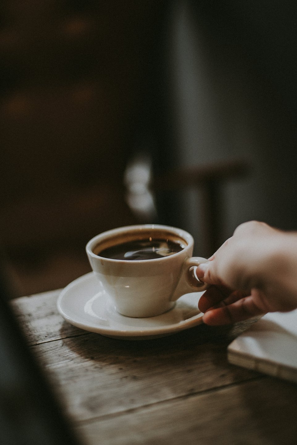 Una mano afferra una tazza da caffè in ceramica bianca.
